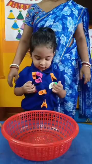 A child sorting colourful shapes with her teacher